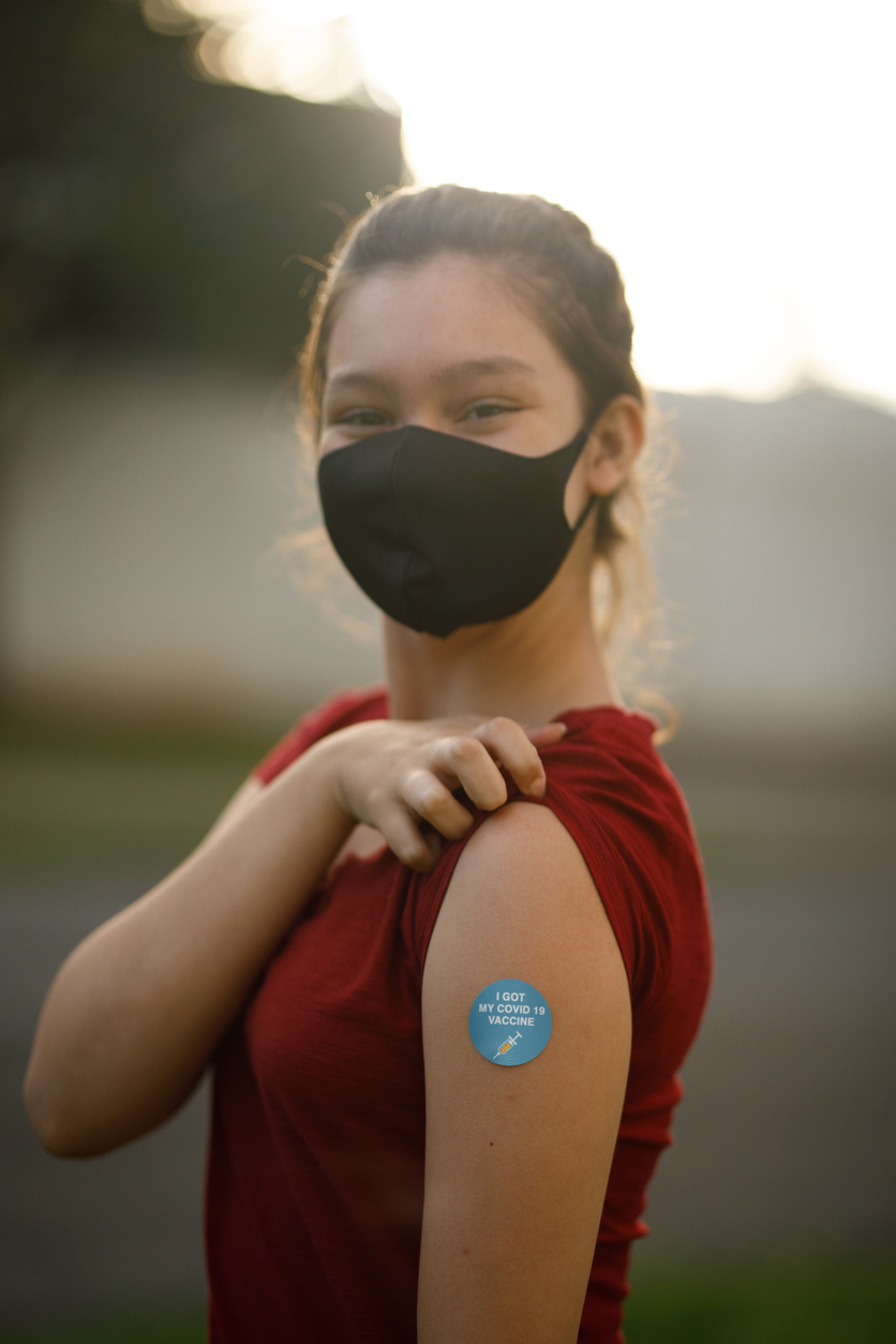 Girl showing her covid 19 vaccine badge